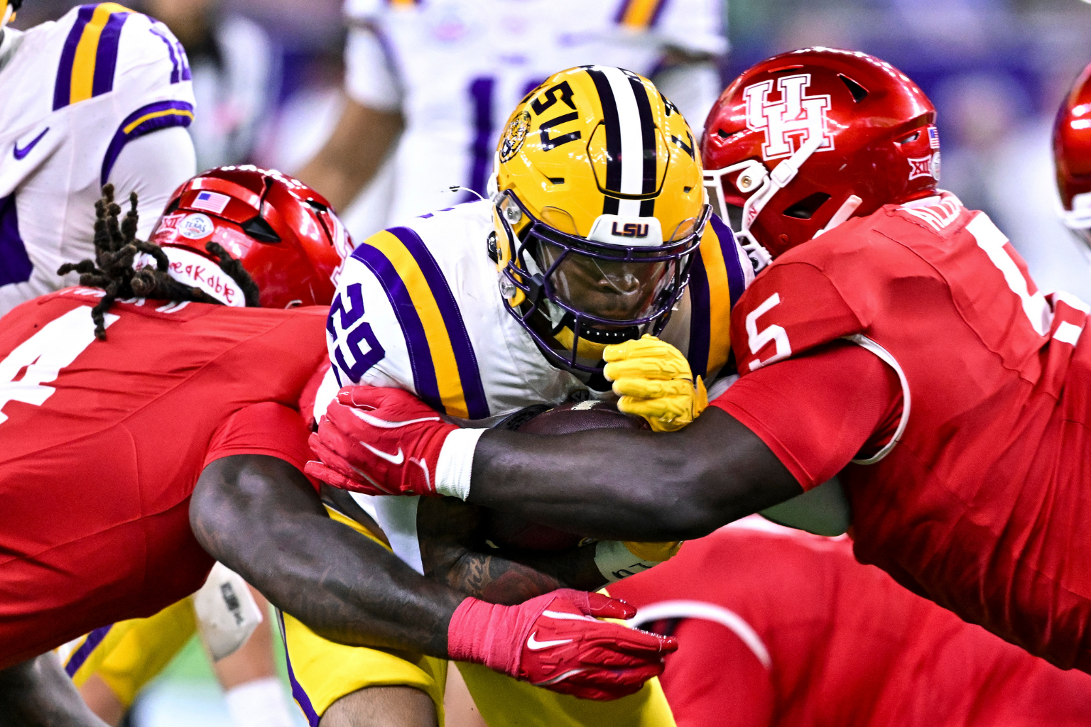 Dec 27, 2025; Houston, TX, USA; Louisiana State Tigers running back Caden Durham (29) runs the ball as Houston Cougars defensive end Brandon Mack (4) and defensive lineman Carlos Allen (5) attempt to tackle during the first half at NRG Stadium.